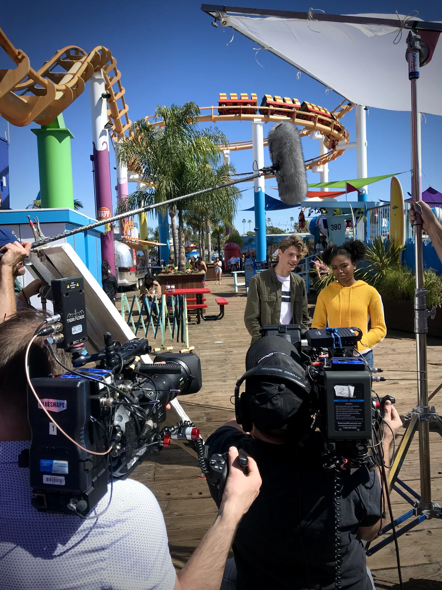 An Artifact Productions crew filming two young actors on Santa Monica Pier